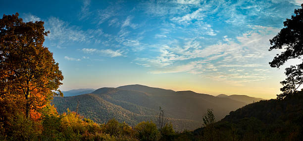 The early morning Autumn sun breaks over the mountains in Shenandoah National Park bringing out the brilliant reds and oranges of the deciduous trees.